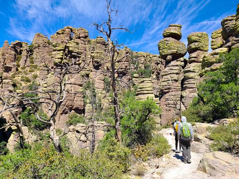 Hikers in front of pillar rock formations with a blue sky