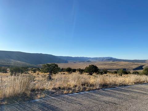 View from a road of a long canyon wall in the desert landscape.