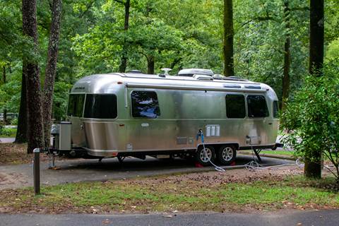 RV parked at campsite in the woods.