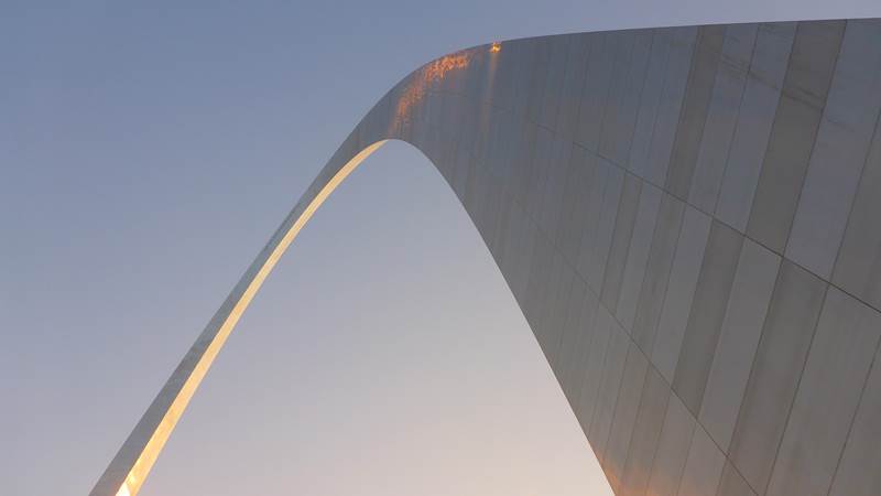 looking up at the curve of the Gateway Arch against the sky